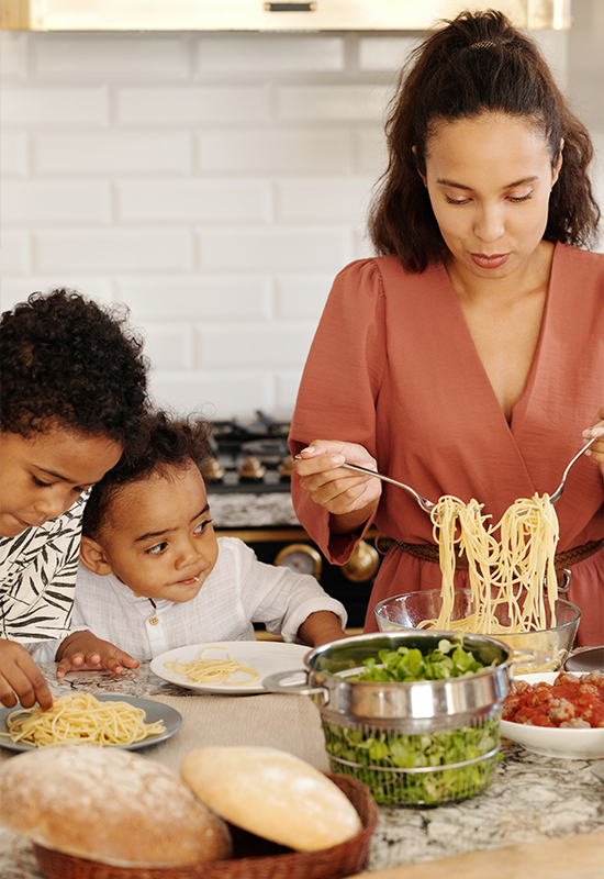 Mom cooking dinner with her two boys snacking