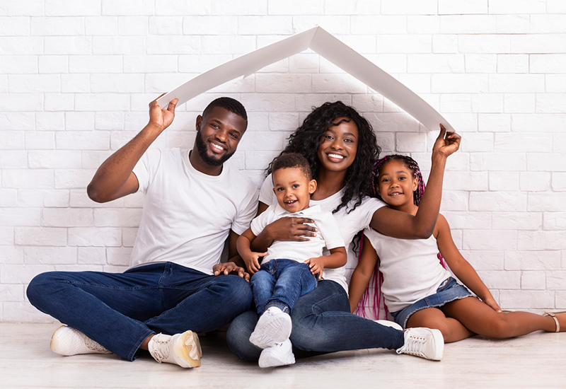 Family sitting under a photo prop roof smiling