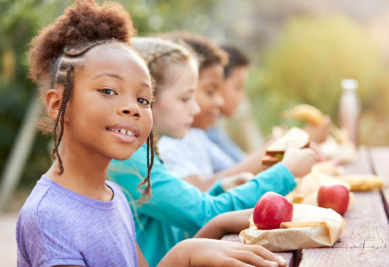 NutritionImage_kids Kids sitting at a picnic table eating lunch