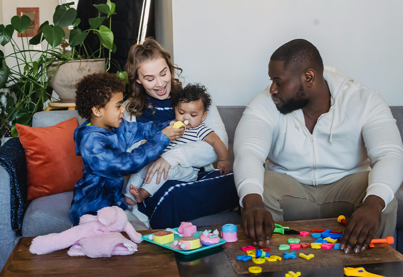 Family of four sitting on the couch playing with toys