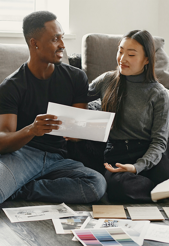 Young diverse couple sitting on the ground looking at swatches