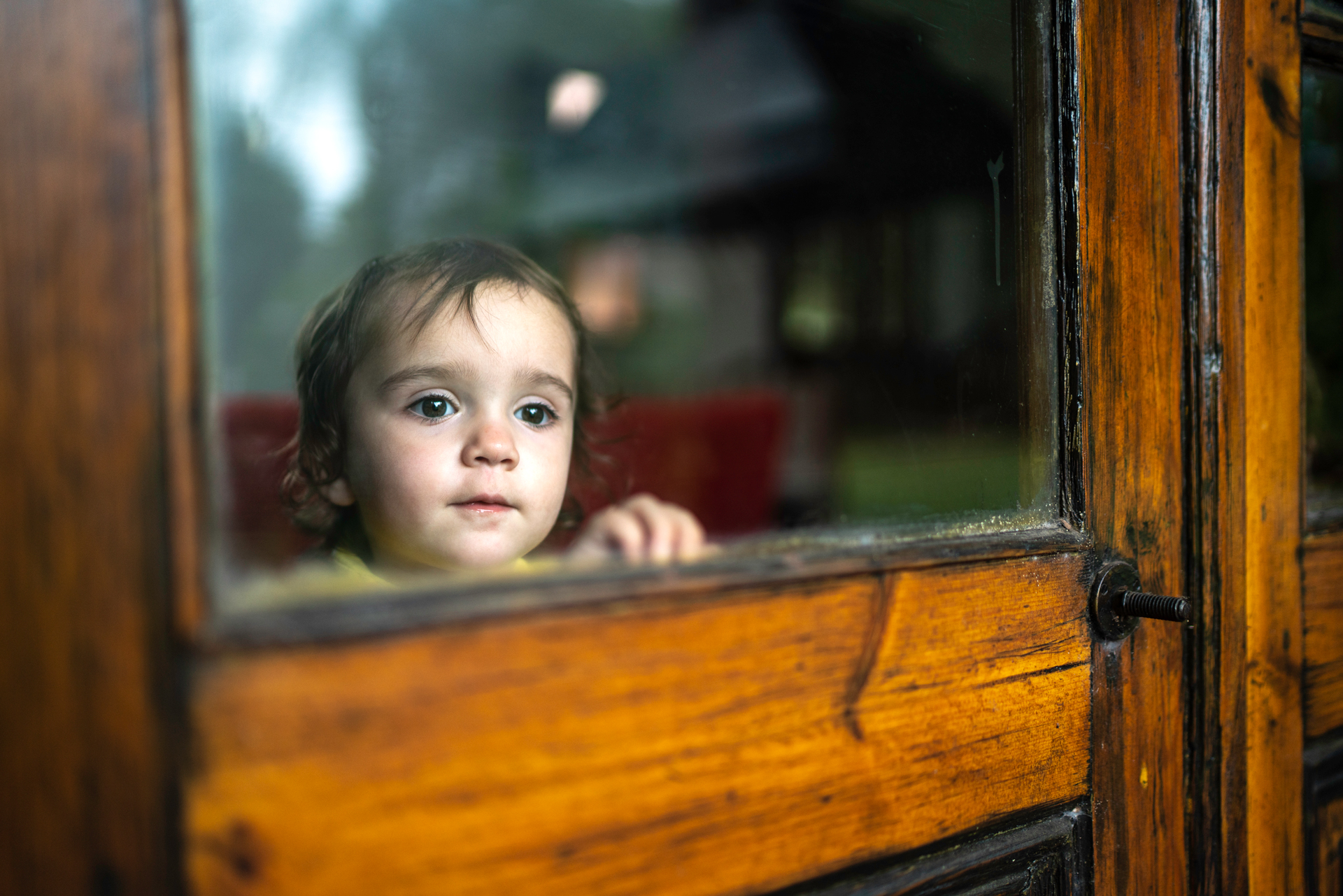 Young child looking out of a glass window door