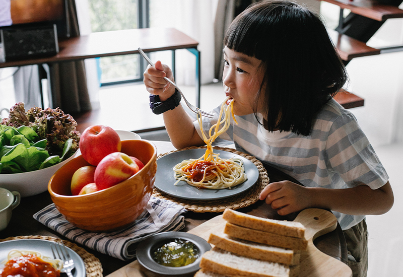 Child eating spaghetti at the table